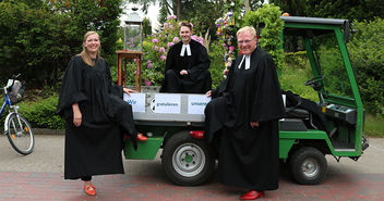 Pastorin Laura Koch-Pauka, Vikar Alexander Bieniasz und Pastor Harald Schmidt sitzen auf einem kleinen Trekker, dem Konfi-Mobil. - Copyright: Sandra Bähr